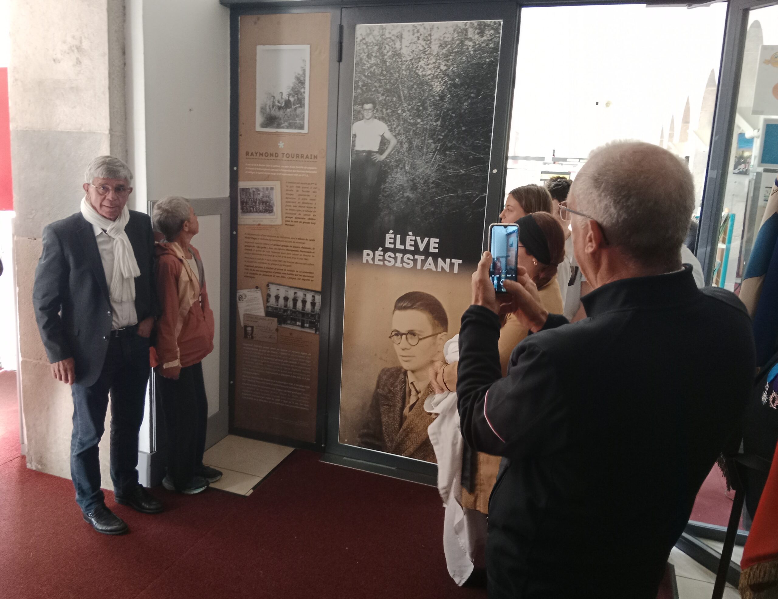 Eleves et professeurs devant l'affiche de nom de Raymond Tourrain